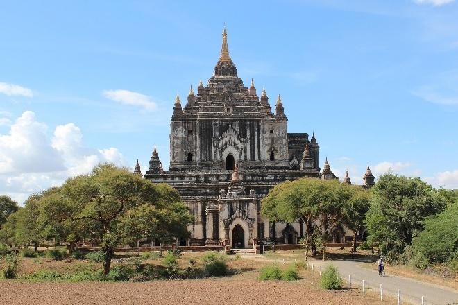 A Buddhist temple with multiple tiered roofs stands majestically against a blue sky with scattered clouds.