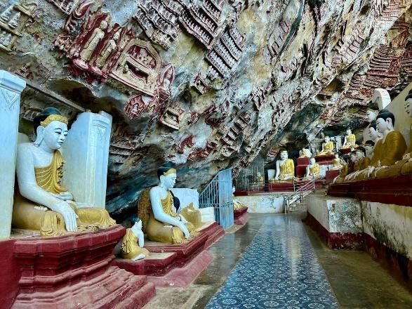 A cave filled with Buddha statues, adorned with intricate carvings and red and gold details, offers a serene and spiritual atmosphere.